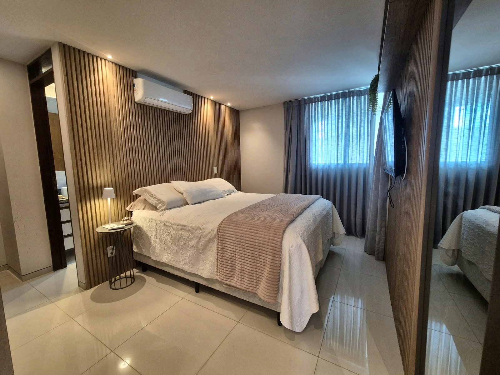 Suíte principal com painel ripado e cama de casal