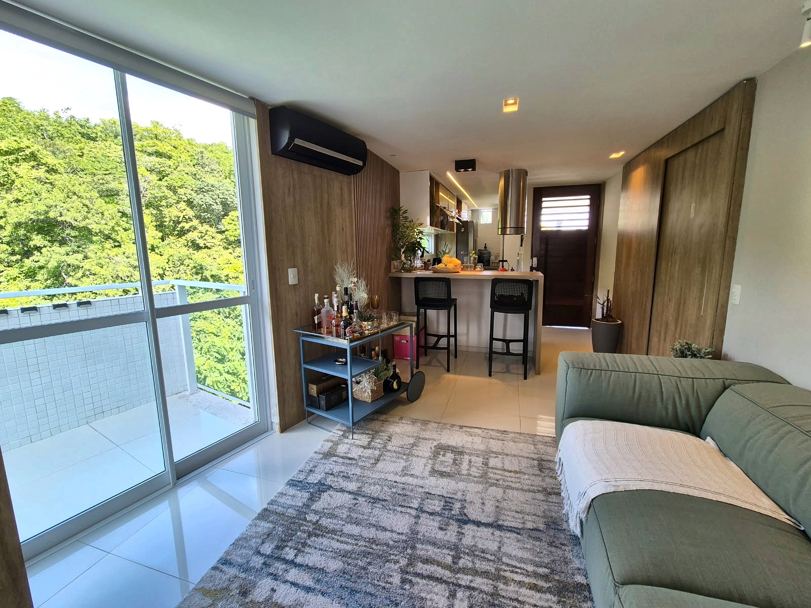 Living integrado à varanda e à cozinha, com vista para a vegetação